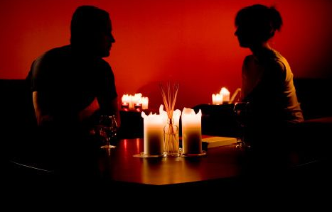 romantico homem e mulher sentado no escuro a luz de velas