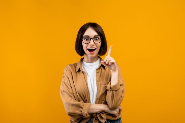 fundo cor de abóbora com mulher apontando dedo pra cima, sorrindo e com olhos arregalados