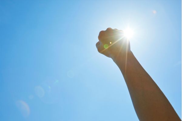 sindrome de penélope braço erguido com punho fechado e o sol e céu azul