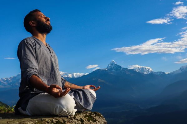 técnicas de energia negativa homem meditando com montanahas no fundo e céu azul