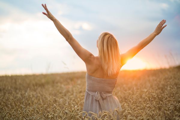 O QUE É A VIDA mulher com braços para o alto olhando para o céu com o por do sol