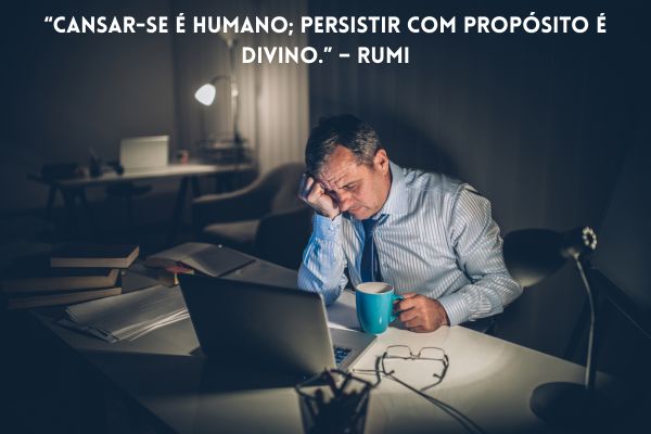 cansado de tudo homem no escuro, sentado, de frente para o computador, com xícara na mão e outra mão no rosto de cansaço
