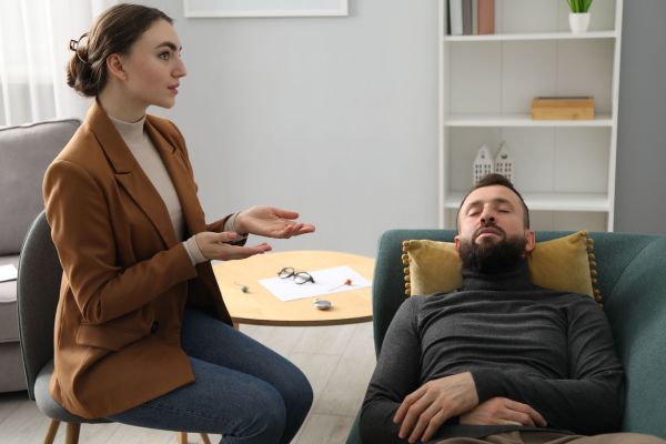 comportamento humano uma mulher sentada e um homem deitado no sofá representando psicanálise