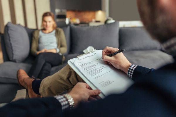 comportamento humano homem com prancheta e uma mulher de fundo representando sessão de terapia