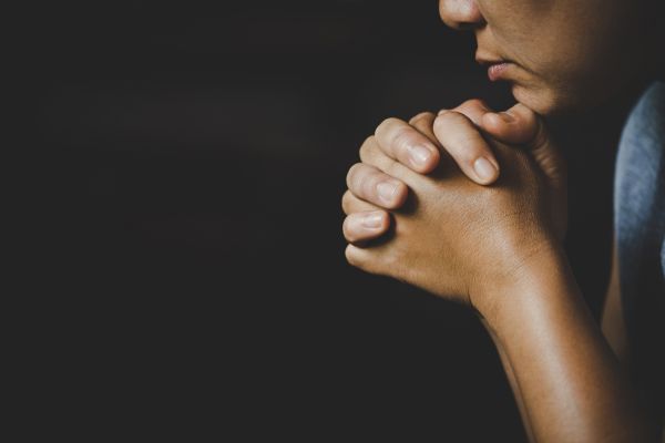pessoa de mãos cruzadas no queixo rezando
