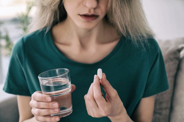 anti depressivo mulher com copo e remédio na mão olhando para ele