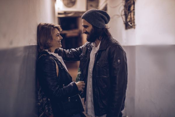 como conquistar mulhers difícieis mulher encostada na parde conversando com um homem representando como conquistar uma mulher