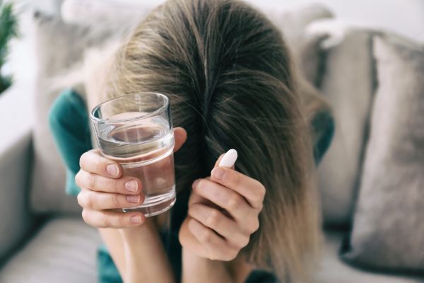 como melhorar abstinência de antidepressivos mulher sentada com copo e remédio com a cabeça abaixada