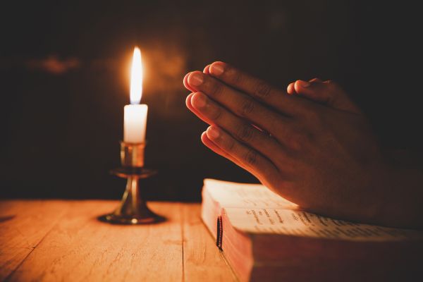 orações pra tirar pensamentos ruins duas mãos juntas em cima da bíblia e uma vela