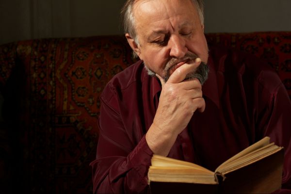 Homem com mão no queixo lendo um livro