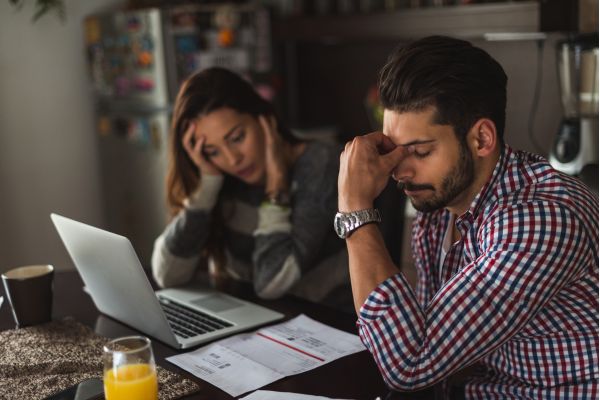 sonhar dívidas homem e mulher sentado de frente para o computador preocupados