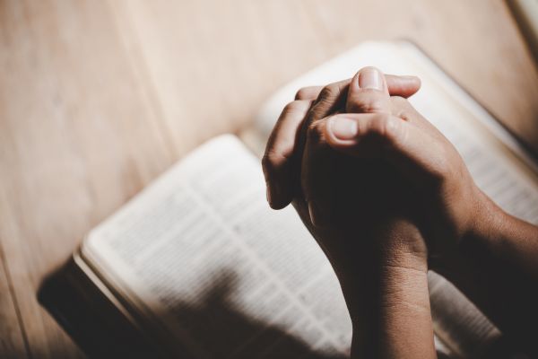 como afastar de pessoas negativas mãos em cima de uma bíblia representando oração