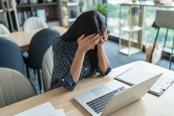 sabotagem mulher com mão no rosto de frente para um laptop