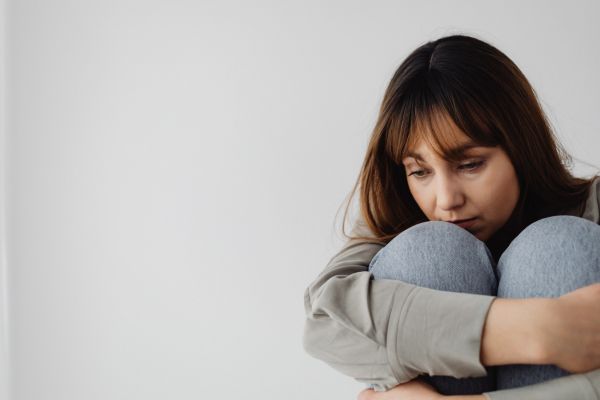 carencia afetiva mulher sentada triste com boca encostando nos joelhos