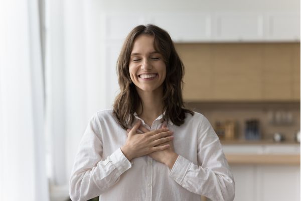como se pratica a gratidão mulher sorrindo com mãos no peito