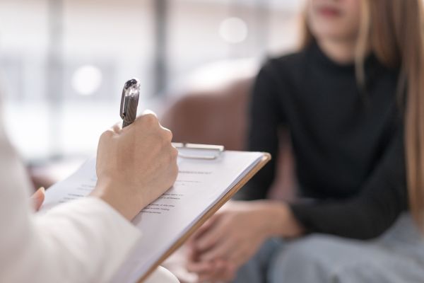mulher de frente para psicologo com prancheta na mão