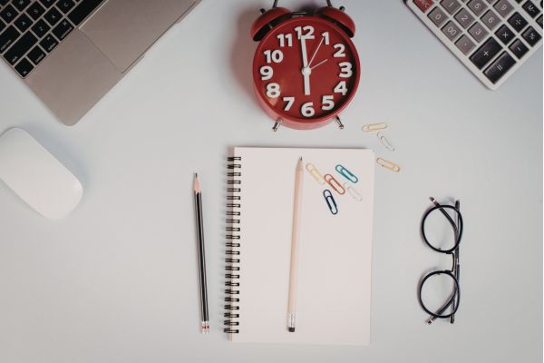mesa organizada com relogio, caderno e computador representando planejamento e gestão do tempo no trabalho