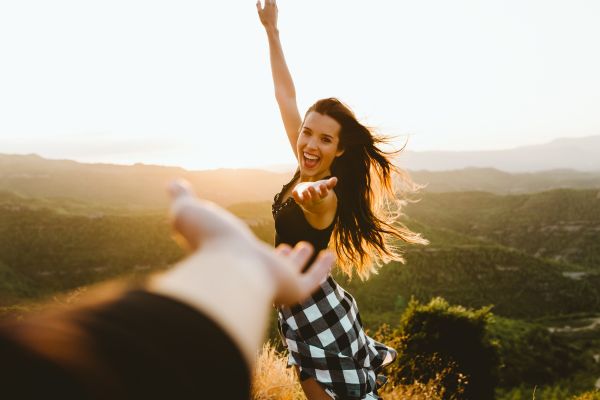 mulher sorrindo esticando o braço para outro braço esticado muito feliz