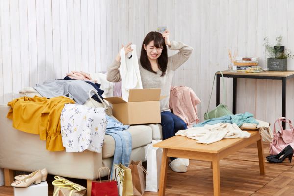 resoluções problemas japonesa coçando a cabeça com monte de roupas ao lado