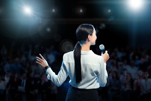 como perder medo de falar em público mulher com microfone no palco dando palestra