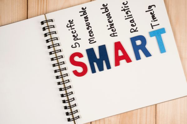 metodo-smart-como-fazer-metas Caderno com a palavra SMART destacando metas específicas, mensuráveis, alcançáveis, relevantes e com prazo definido