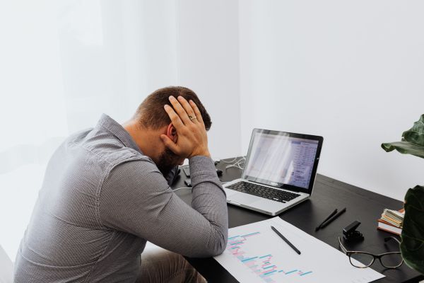 estresse trabalho mindfulness homem de frente para laptop com mão na cabeça represetnando estresse
