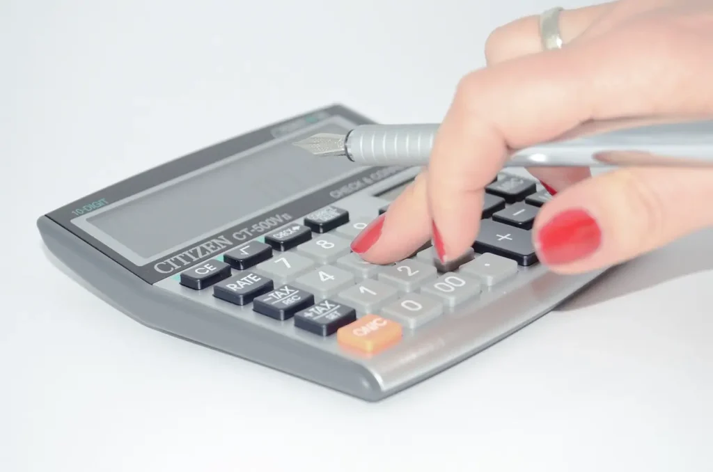 riqueza Pessoa calculando finanças pessoais em calculadora com caneta na mão