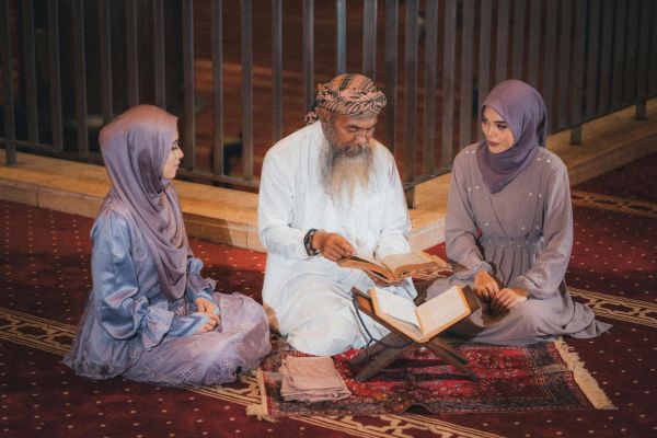 duas mulheres e um homem com livro aberto representando um guru espiritual