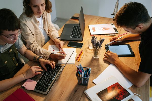 dois jovens e uma garota reunido numa mesa represetnando trabalho