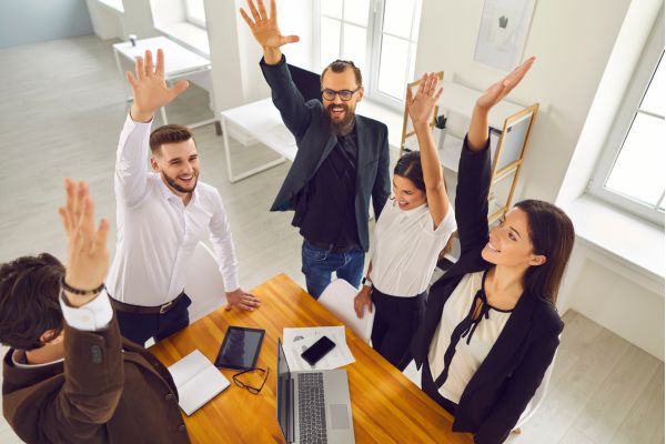 textos motivacionais trabalho em equipe pessoas em volta da mesa com braços levantados