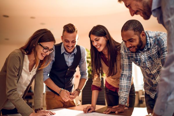 textos motivacionais trabalho em equipe pessoas de bruço em cima de uma mesa sorrindo e olhando para um papel