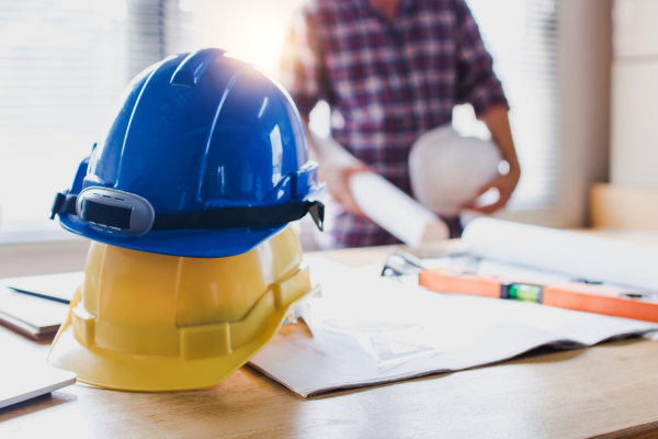 uma pessoa e 2 capacetes de segurança do trabalho