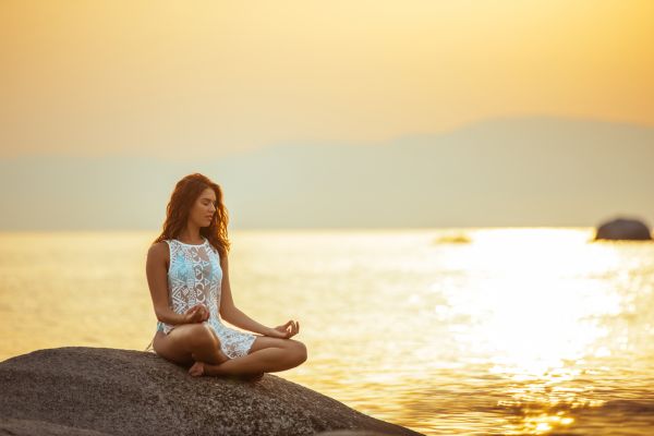 despertar conexão com todo mulher na pedra sentada meditando de frente para o mar