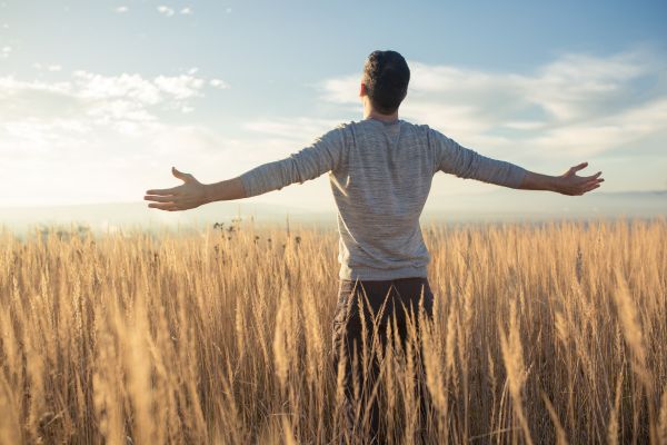despertar crenças no meio da plantação homem de braços abertos olhando para o céu