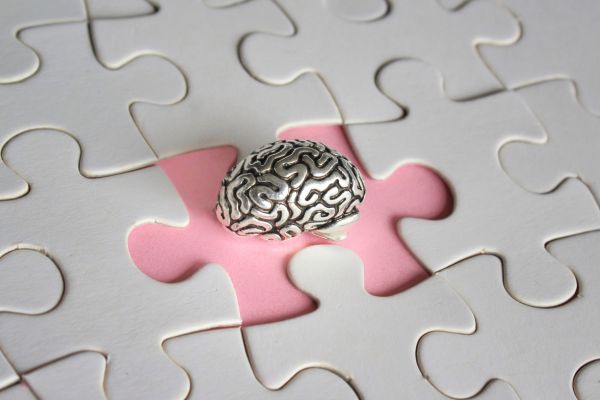bloqueios emocionais saude mental relação cerebro Imagem conceitual mostrando a relação entre bloqueios emocionais e saúde mental, representada por um cérebro como peça de quebra-cabeça simbolizando integração emocional e equilíbrio psicológico.