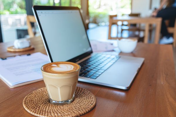rotina matinal produtividade cafe notebook café ao lado de notebook em mesa iluminada pela manhã representando rotina matinal e produtividade