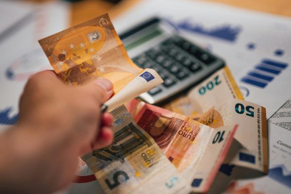 como aumentar a sua renda dinheiro calculadora finanças mão segurando dinheiro ao lado de calculadora representando aumento de renda e controle financeiro