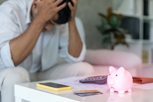 homem preocupado com dívidas olhando contas e cartão de crédito