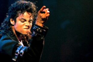 Michael Jackson cantando e dançando durante apresentação no palco com expressão intensa.