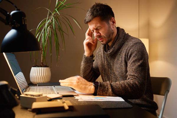 definição cansaço mental sobrecarga mental Homem trabalhando no laptop demonstrando cansaço mental e sobrecarga cognitiva