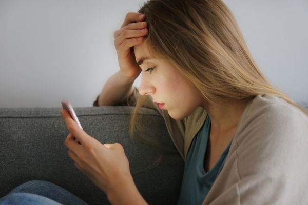 Mulher preocupada olhando o celular representando erros que alimentam a comparação social nas redes sociais