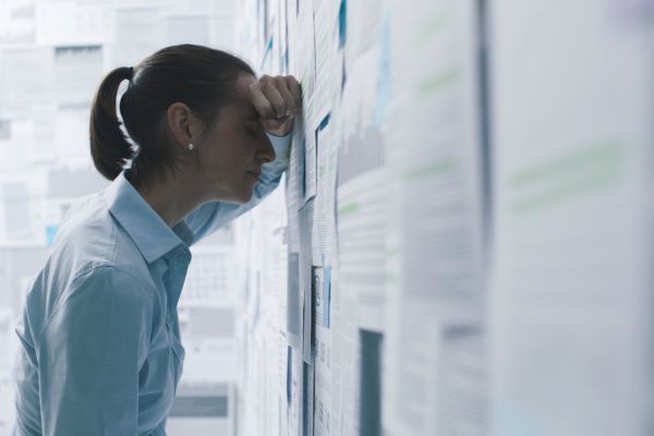 fracasso financeiro pressao mental Pessoa estressada analisando documentos, representando o impacto emocional do fracasso financeiro