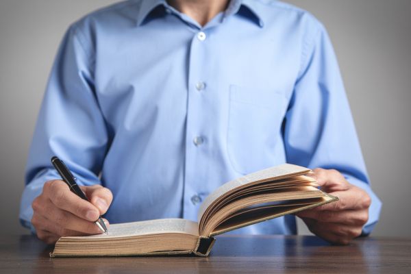 leitura de autores desenvolvimento do pensamento Pessoa lendo e fazendo anotações em um livro, representando o desenvolvimento do pensamento por meio da leitura de autores.