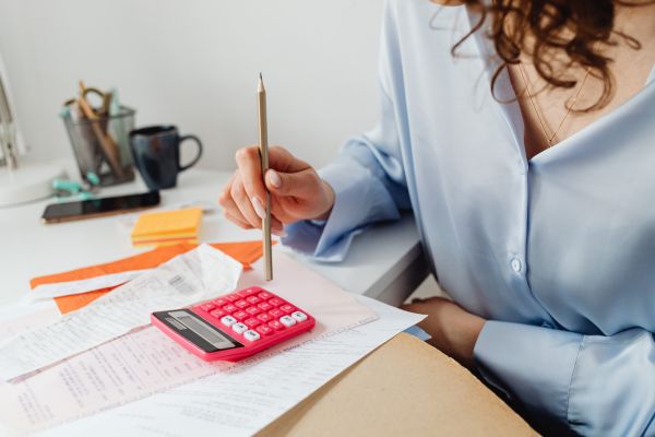 nao investir em educação financeira Pessoa analisando contas e usando calculadora representando a importância da educação financeira para evitar erros com dinheiro.