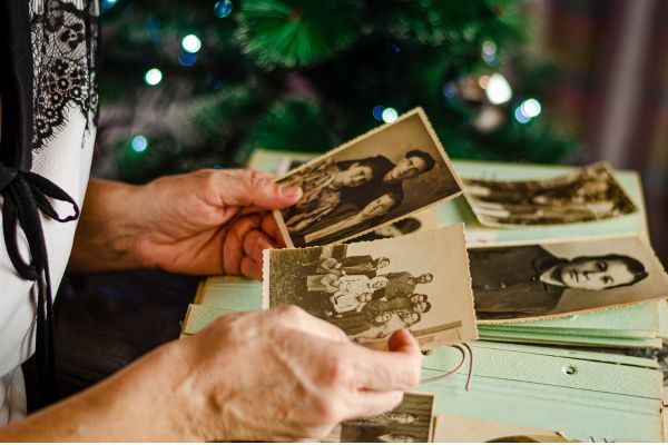 tipos de saudade da pessoa que ja fomos memorias Pessoa segurando fotografias antigas que representam lembranças e diferentes fases da vida.