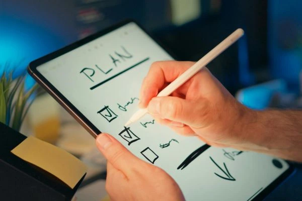 como-priorizar-tarefas-no-planejamento-semanal Pessoa organizando uma lista de tarefas em um tablet, representando como priorizar tarefas no planejamento semanal