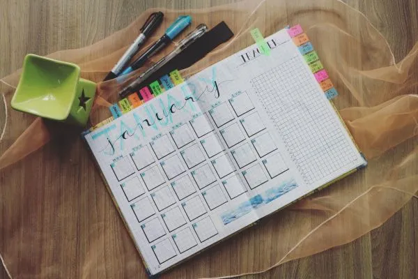 Agenda aberta com calendário mensal e anotações, representando o planejamento semanal para organizar a semana com mais produtividade.
